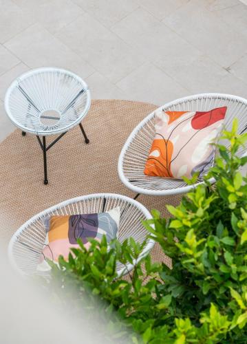 three white chairs and a table with a pillow on it at Villa Ilma Luxury Rooms in Arzachena