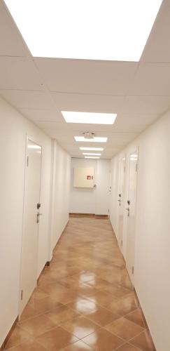 a hallway in an office building with white walls and a ceiling at Systra Hotel Søvik in Syvik