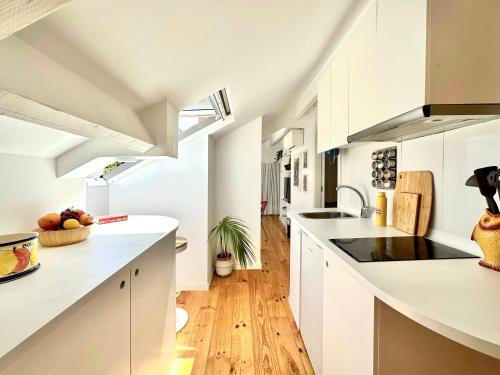 a kitchen with white cabinets and a wooden floor at Art Cottage with oPorto View! in Vila Nova de Gaia