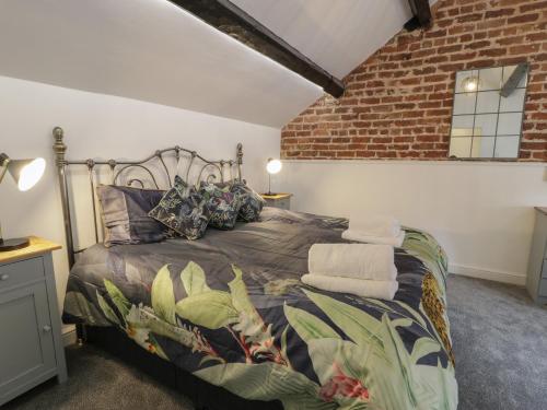 een slaapkamer met een bed en een bakstenen muur bij Conors Cottage in Denbigh