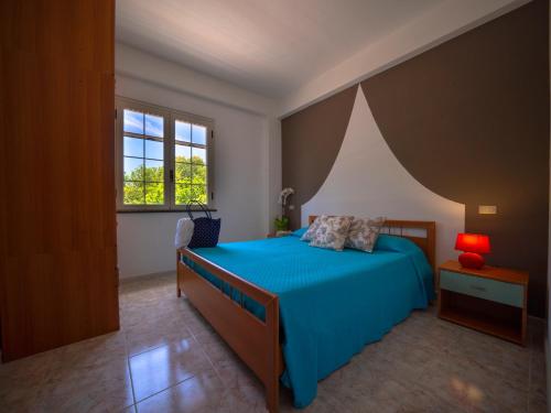 a bedroom with a blue bed and a window at Residence Olimpo in Capo Vaticano
