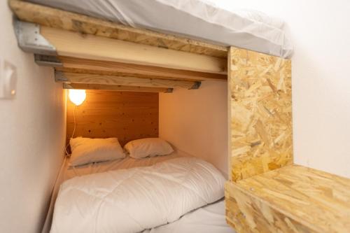 a bed in a small room with a wooden wall at Les Anglines - Appt proche station de ski in Les Angles