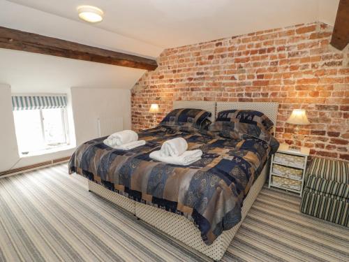 Walled Garden Cottage في دنبي: غرفة نوم بحائط من الطوب وسرير مع وسادتين