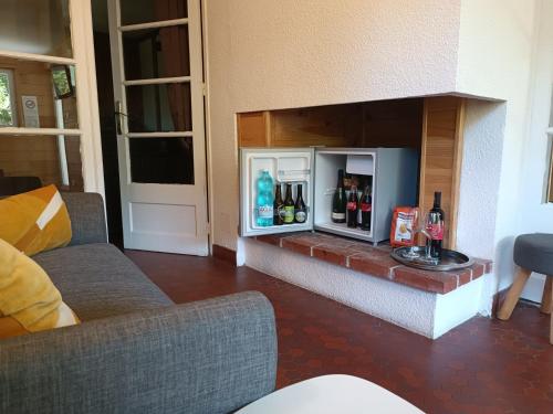 a living room with a fireplace with a small refrigerator at L'Imprévu in Bourisp