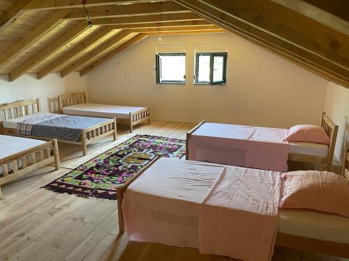 a room with three beds and a rug at Guesthouse Tropojë e Vjeter in Tropojë