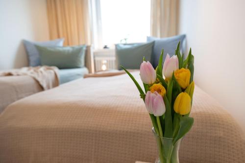 a vase filled with flowers sitting next to a bed at Ferienwohnung WetterFest 11 in Wittdün
