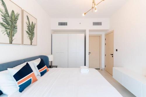 een witte slaapkamer met een wit bed met blauwe accenten bij New unit l Pool View l Easy Exit in Dubai