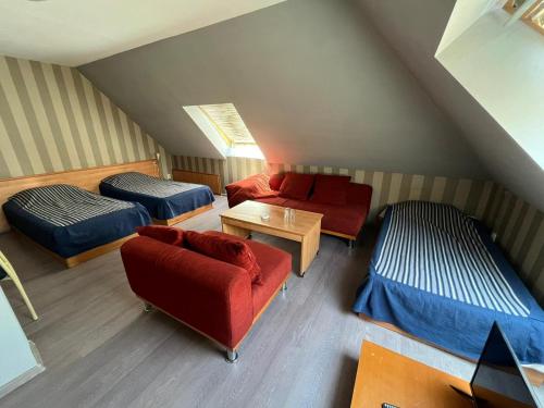 Cette chambre mansardée comprend deux lits et un canapé rouge. dans l'établissement HOTEL KREDO, à Sliven