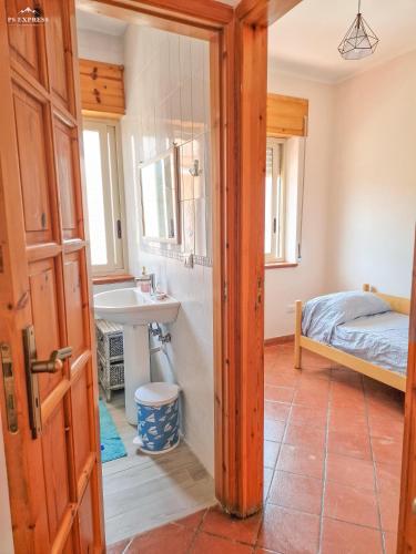 La salle de bains est pourvue d'un lavabo et d'un lit dans la chambre. dans l'établissement Wanderlust Sicily appartamento "Mare", à Oliveri