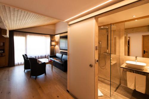 a bathroom with a sink and a shower in a room at Hôtel Cailler & Bains de la Gruyère in Charmey