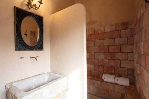 a bathroom with a brick wall and a mirror at Commanderie de Peyrassol- Bastide de La Rouvière in Flassans-sur-Issole