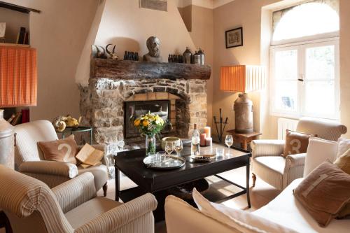 a living room with a stone fireplace and a table at Commanderie de Peyrassol- Bastide de La Rouvière in Flassans-sur-Issole