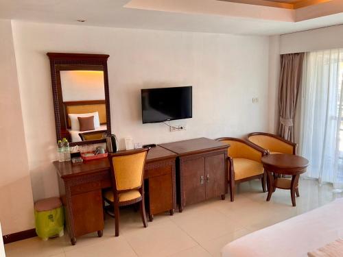 a hotel room with a desk with chairs and a television at Sota Residence in Pattaya South