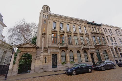 a large building with two cars parked in front of it at Cozy Antwerp - Zurenborg Skyline in Antwerp