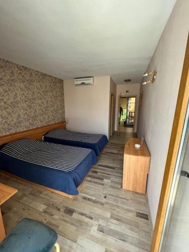 a room with two beds and a wooden table at HOTEL KREDO in Sliven