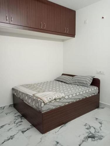Cama en habitación blanca con cabecero de madera en Variyar Service Apartments Unit C 1st Floor, en Vellore