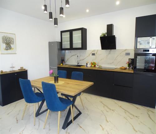 cocina con mesa de madera y sillas azules en Holiday house Parancin, en Stankovci