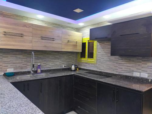 a kitchen with wooden cabinets and a sink and a counter at شقه فندقيه in Cairo
