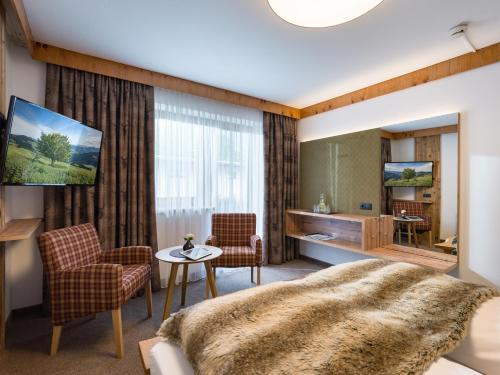 um quarto com uma cama, uma mesa e cadeiras em Hotel Landhaus Zillertal em Fügen