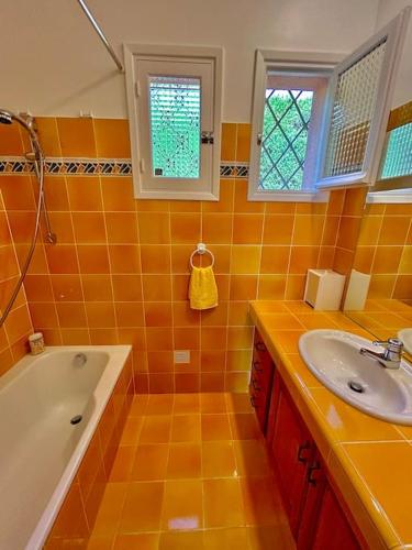 La salle de bains est pourvue de carrelage orange, d'une baignoire et d'un lavabo. dans l'établissement Havre de paix vue mer & piscine privée, à Espéro-Pax