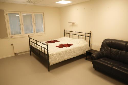 1 dormitorio con cama y sofá de cuero en Skrå hostel - bed & business, en Släda