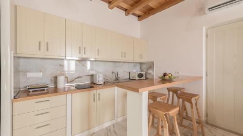 a kitchen with white cabinets and a counter with stools at Milion Fantasy House in Adamas