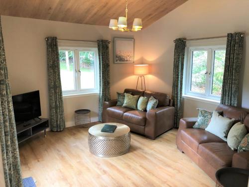 a living room with a couch and a coffee table at Breckland Lodge 2 with Hot Tub in Belladrum