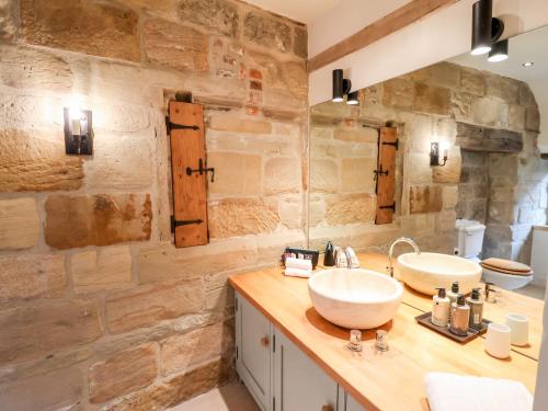 a bathroom with two sinks and a stone wall at Tithe Barn in Derby