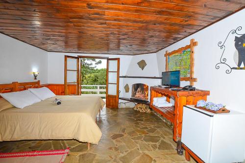 a bedroom with a bed and a desk with a television at Hotel Cabeça de Boi in Monte Verde