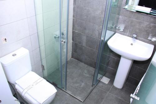 a bathroom with a shower and a toilet and a sink at Beverly Hotel Beirut in Beirut