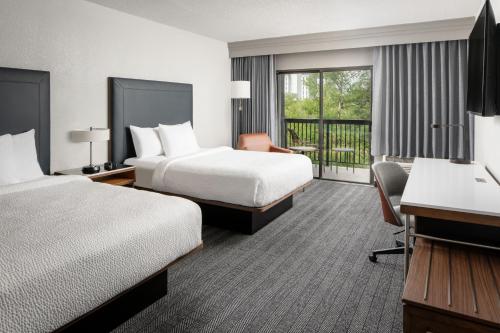 a hotel room with two beds and a balcony at Courtyard by Marriott New Orleans Metairie in Metairie
