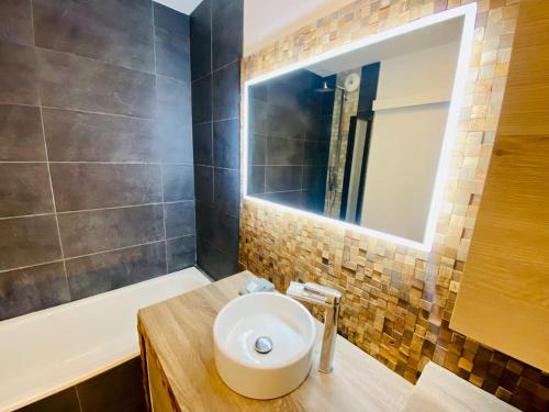 a bathroom with a sink and a mirror and a tub at ''Le Soleil'' Superbe T3 avec vue étang et mer, clim parking et piscine in Sète