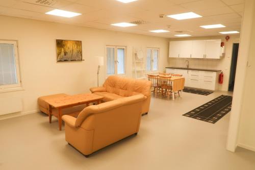 a living room with chairs and a table and a kitchen at Skrå hostel - bed & business in Alnön