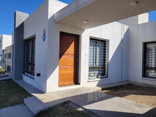eine Holztür auf einem weißen Haus mit Fenstern in der Unterkunft Casa Amplia y Tranquila con Garage in Alta Gracia