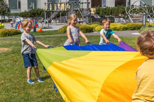 three children playing with a large kite in a park at Hotel Aquarius SPA in Kołobrzeg