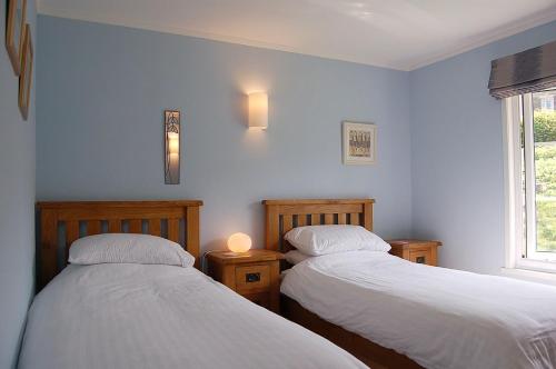 2 camas en una habitación con paredes azules en Cae Talgarth Bungalow at Plas Talgarth Resort, en Pennal