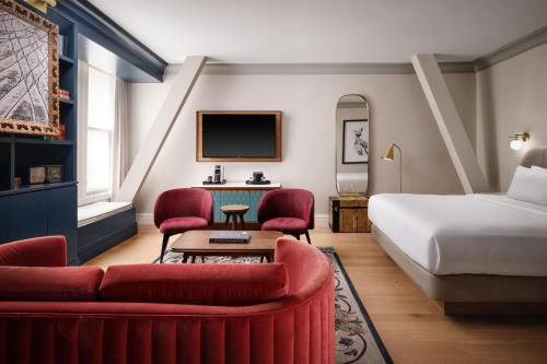 a hotel room with a bed and red chairs at The Union Station Nashville Yards, Autograph Collection in Nashville