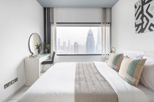 a white bedroom with a large bed and a window at Frank Porter - Index Tower in Dubai