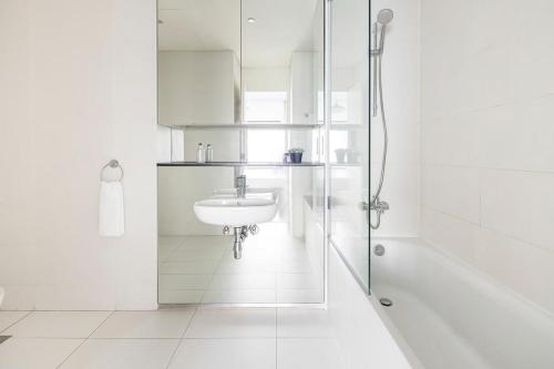 a white bathroom with a sink and a shower at Frank Porter - Index Tower in Dubai