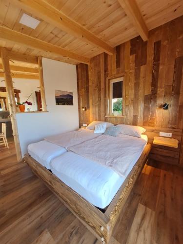 a large bed in a room with wooden walls at Panorama glamping Vipavska dolina in Dobravlje