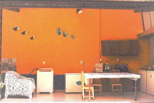 Habitación con pared de color naranja, mesa y sillas. en Hostal mburucuyá, en Ciudad del Este