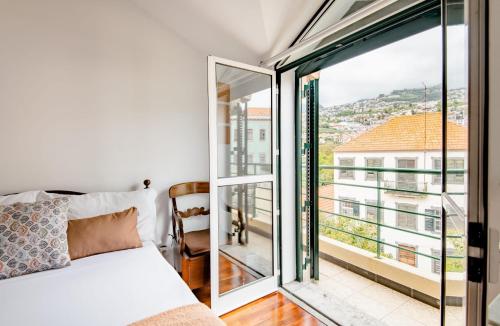 ein Schlafzimmer mit einem Bett und einem großen Fenster in der Unterkunft A ver o mar rooms- Funchal city center in Funchal