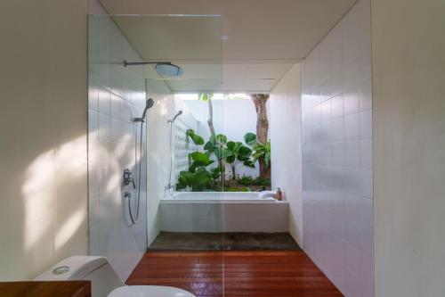 a bathroom with a shower and a toilet and a window at Ayom Suite in Mataram