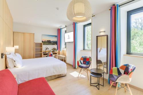 1 dormitorio con 1 cama y sillas en una habitación en La Cachette, en Dieulefit