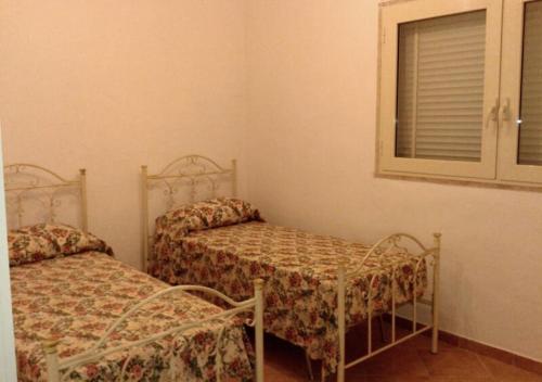 a bedroom with two beds and a window and a mirror at Casa Giovanni by My Home Apulia in Torre Lapillo