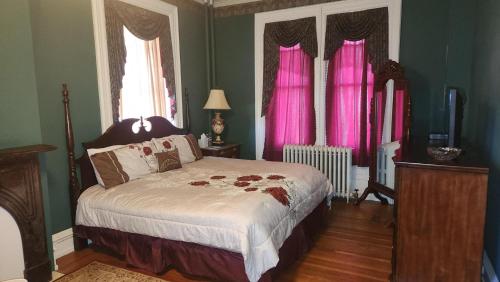 a bedroom with a large bed with pink curtains at Greystone Manor Bed & Breakfast in Bird in Hand