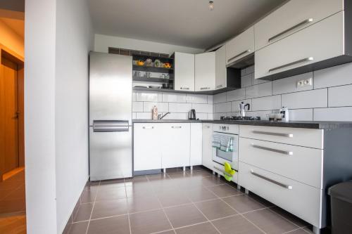 een keuken met witte apparatuur en een tegelvloer bij Friends & Family Apartment in Trenčín