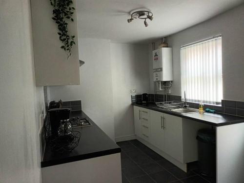 a kitchen with white cabinets and a black counter top at Antonio str Liverpool 6 beds in Liverpool