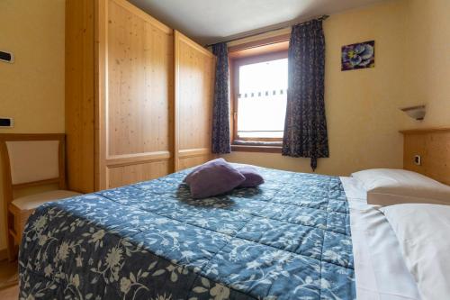a bedroom with a bed with a blue blanket and a window at Appartamento Levanto in Livigno