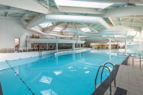 a large swimming pool with blue water in a building at Village Pierre & Vacances Belle Dune in Fort-Mahon-Plage